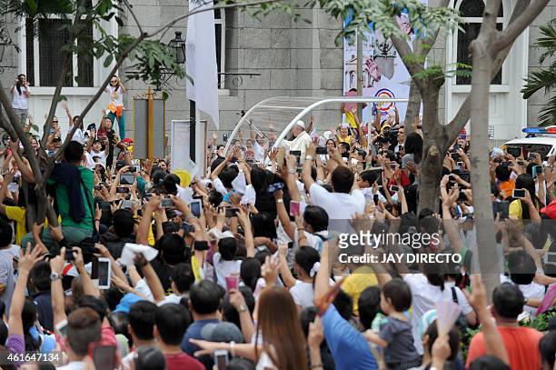In this picture taken on January 16 Pope Francis waves to well-wishers as he arrives at the Manila Cathedral to say mass to bishops and priests in...