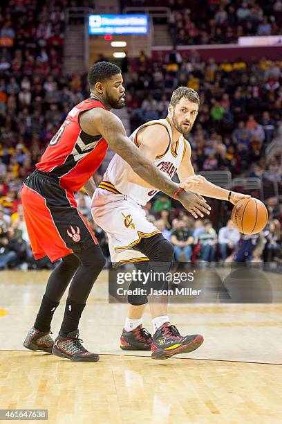 Amir Johnson of the Toronto Raptors blocks Kevin Love of the Cleveland Cavaliers during the first half at Quicken Loans Arena on December 9, 2014 in...