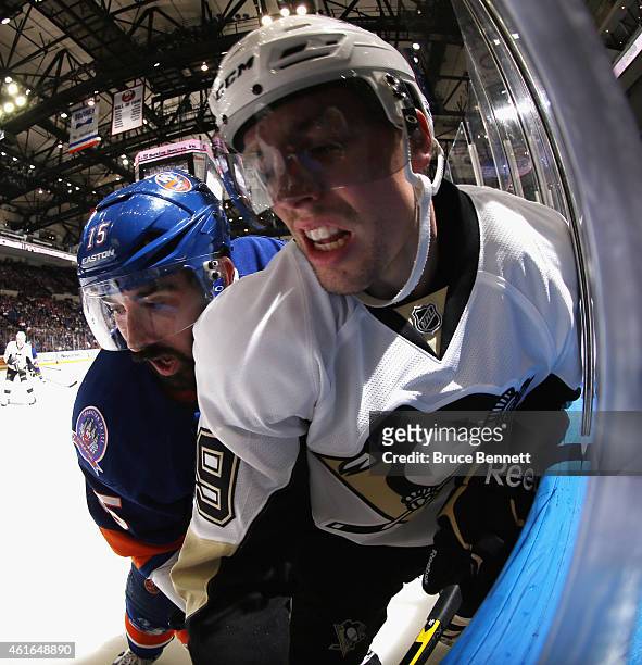 Cal Clutterbuck of the New York Islanders rides David Perron of the Pittsburgh Penguins into the glass during the second period at the Nassau...
