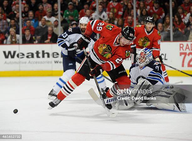 Bryan Bickell of the Chicago Blackhawks tries to control the puck in front of Michael Hutchinson of the Winnipeg Jets during the second period on...