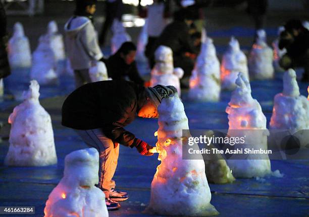 Boy lights a candle placed in a snow statue of Ksitigarbha to mark the 20th anniversary at Yasui Elementary School on January 17, 2015 in...