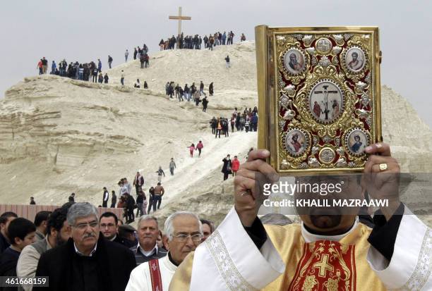 Priest raises up a Bible during an annual pilgrimage to the Baptism Site in Bethany, Jordan, on January 10, 2014. Pope Francis's visit to the Middle...