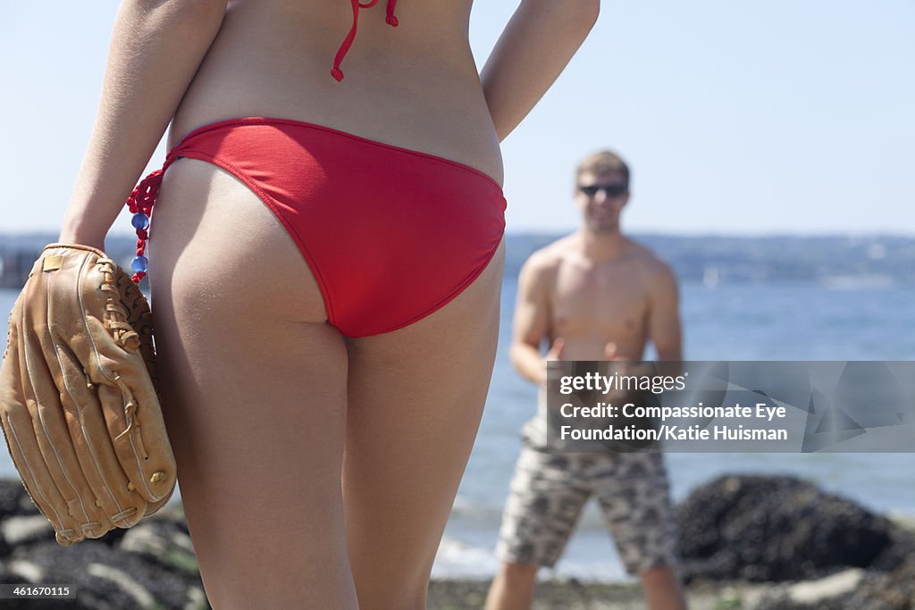 Couple playing baseball on beach