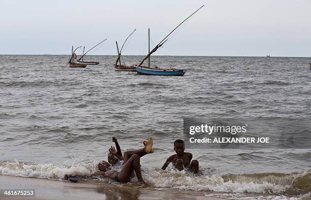 Young children play in the water on a beach in Maputo on January 10, 2014. AFP PHOTO / ALEXANDER JOE