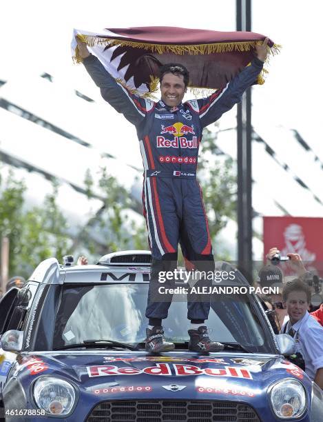 Mini's driver Nasser Al-Attiyah of Qatar winner of the 2015 Dakar Rally auto category, holds a Qatar flag as celebration on the podium in Buenos...