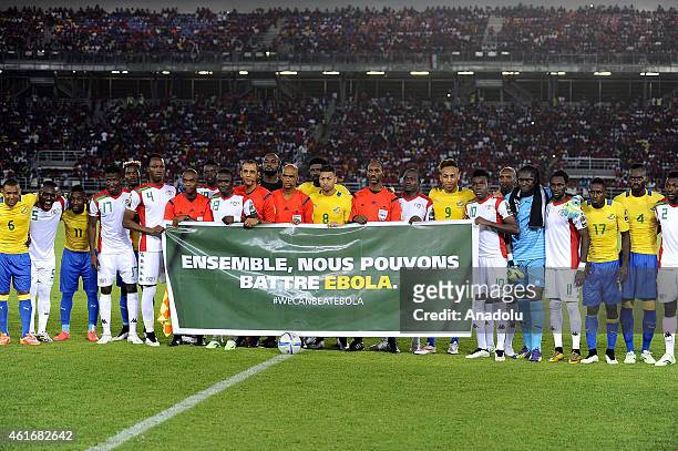 Players of Burkina Faso and Gabon hold a banner reading "Together, we can beat Ebola" ahead of the Group A soccer match between Burkina Faso and...