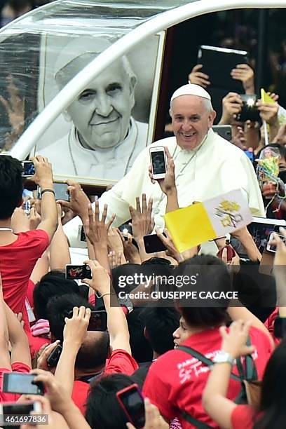 Pope Francis waves as he arrives for a meeting with youths at the University of Santo Tomas in Manila on January 18, 2015. Pope Francis will...