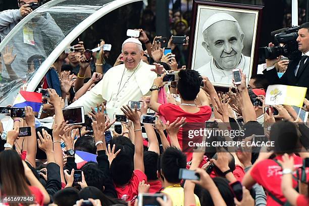 Pope Francis waves as he arrives for a meeting with youths at the University of Santo Tomas in Manila on January 18, 2015. Pope Francis will...