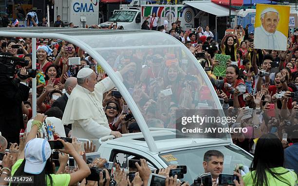 Pope Francis waves as he arrives at the University of Santo Tomas during his visit to Manila on January 18, 2015. Pope Francis celebrated mass with...