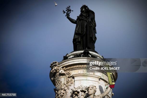 Picture taken on January 18, 2015 shows a giant pencil reading 'Je suis Charlie' set up on the arm of a relief adoring the plinth of the statue of...