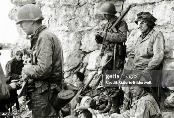 These soldiers from the1st Infantry Division are protected from German fire at the foot of the cliff of Colleville-sur-Mer. 6th June 1944. This is...