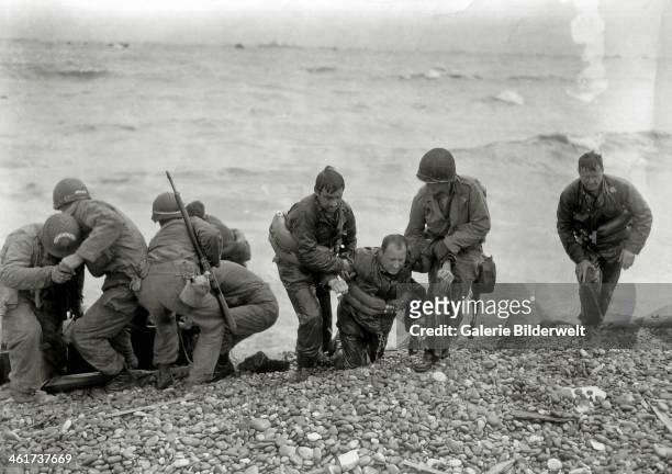 Soldiers rescue others from the sea on Omaha Beach during the Normandy Landings, 7th June 1944. Photo: Louis Weintraub. Colleville-sur-Mer, Normandy,...