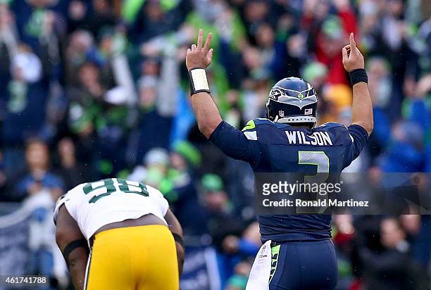 Russell Wilson of the Seattle Seahawks celebrates as Letroy Guion of the Green Bay Packers is in anguish after Wilson threw a game winning touchdown...