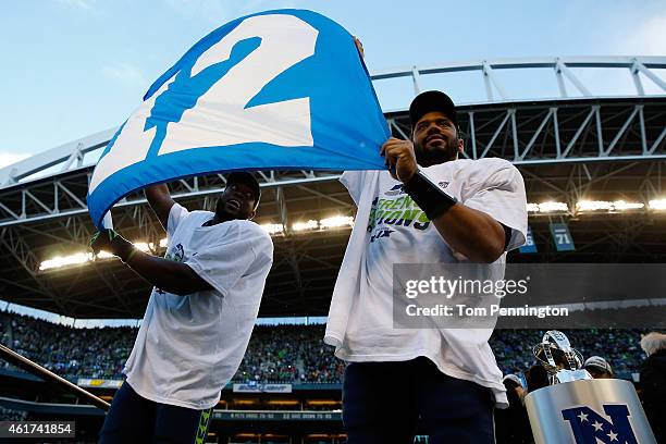 Kam Chancellor and Russell Wilson of the Seattle Seahawks celebrate with a 12th Man flag after defeating the Green Bay Packers in the 2015 NFC...