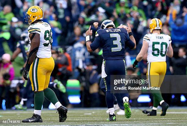 Russell Wilson of the Seattle Seahawks celebrates as Letroy Guion of the Green Bay Packers is in anguish after Wilson threw a game winning touchdown...