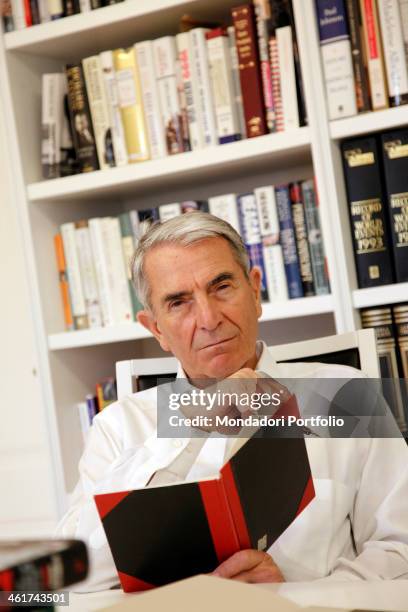 The Italian journalist Carlo Rossella poses with a book in his study. Pavia, 9th March 2012