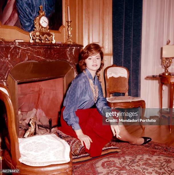 The Croatian actress Sylva Koscina seated in front of a fireplace and wearing a red skirt and an indigo blouse; the actress, who moved to Italy when...