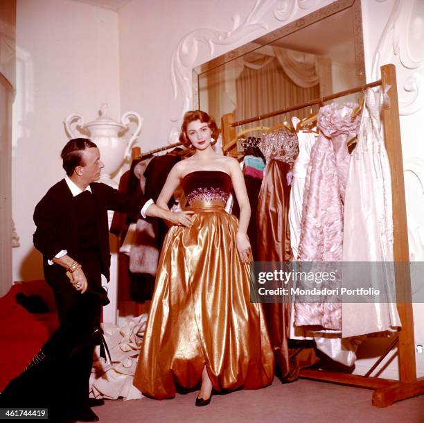 The Croatian actress Sylva Koscina is wearing a golden dress in a costume house under the eyes of a careful tailor; the actress, who moved to Italy...