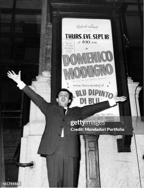 Italian singer and songwriter Domenico Modugno rises his arms , standing before the playbill of the Carnagie Hall, displaying his name in the show...