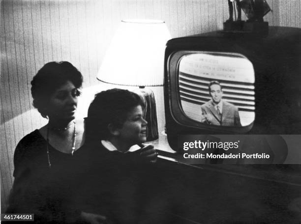 The Italian radio and television host Corrado Mantoni in a TV show; his son Roberto is watching on TV and is smiling under the watchful eye of his...