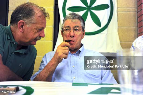 By the rower club of Corgeno, the founder of the political movement Northern League Umberto Bossi lights a cigar under the eyes of Giuseppe Leoni,...