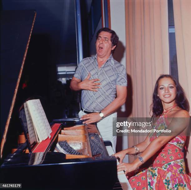 Italian TV and radio author and host Corrado singing at the top of his voice while his assistant Dora Moroni playing piano. Italy, 1976