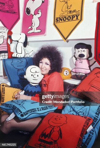 Italian singer Marcella Bella sitting beside soft toys, posters and pillows portraying Charlie Brown, Snoopy and Lucy, the characters of the comics...