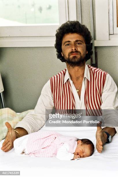 Italian comedian Beppe Grillo measuring with his hands the length of his daughter Luna, just born. 1980