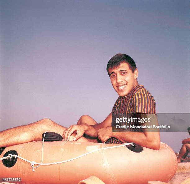Italian singer-songwriter and actor Adriano Celentano sitting in a rubber boat. Italy, 1962