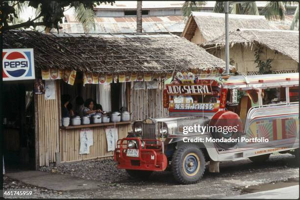 Jeepney, the typical public transport used in the Philippines, parked in front of a restaurant. Philippines, 1970s