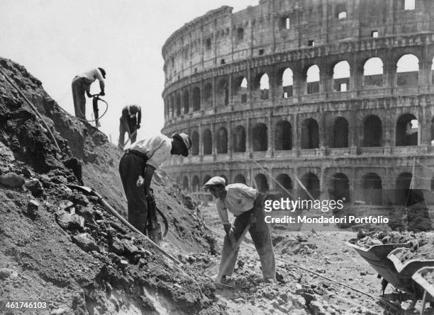 Some workers using axes and drills to build via dell'Impero nearby the Colosseum. Rome, 1930s