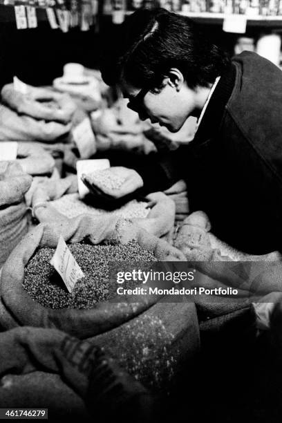 Japanese tourist looking at goods sold by a macrobiotic shop. Milan, 1971