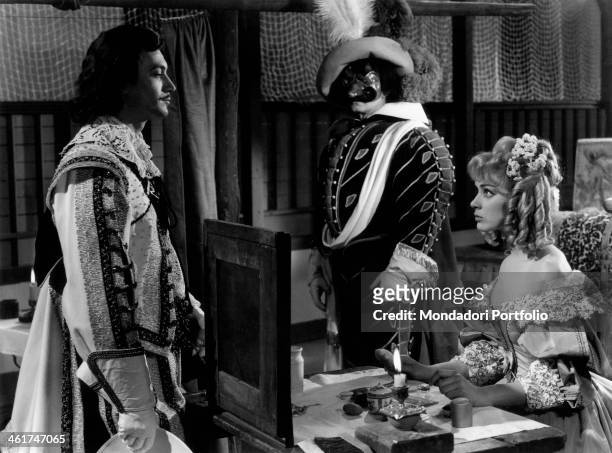 French actress Geneviève Grad talking to French actor Gérard Barray while French actor Jean Marais looking at them wearing a mask in the film Captain...