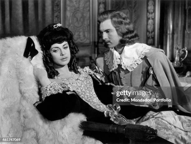 French actor Jacques Toja holding by the hand Italian actress Anna Maria Ferrero lying on a chaise longue in the film Captain Fracasse. France, 1960