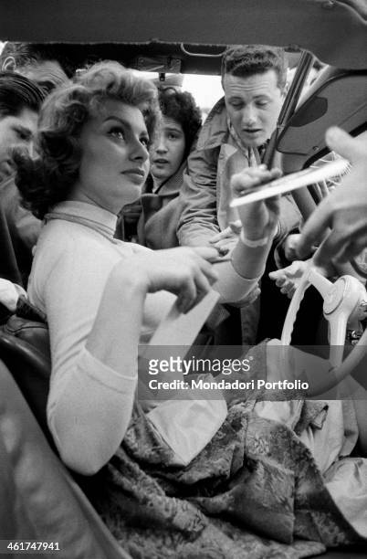 Italian actress Sophia Loren signing autographs seated into her Mercedes. The actress is taking part in third Cinema Rally. Bologna, 1956