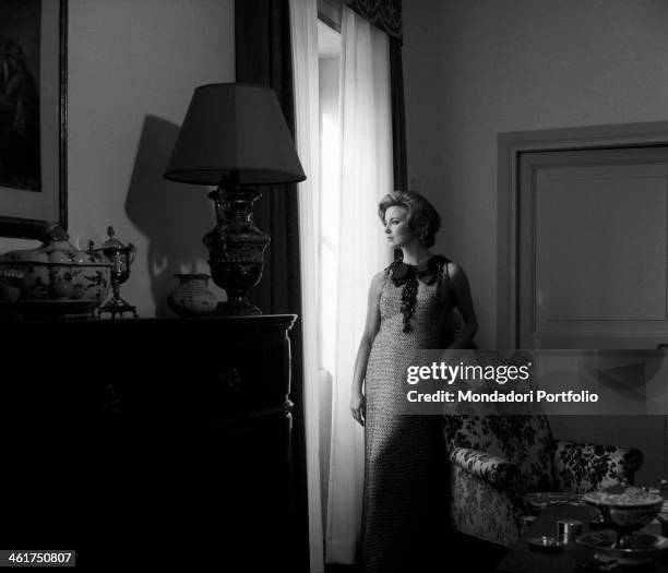 The actress Ilaria Occhini, wearing a stylish long dress with lace collar, in the middle of the sitting room of her tasteful Roman flat, looks out of...