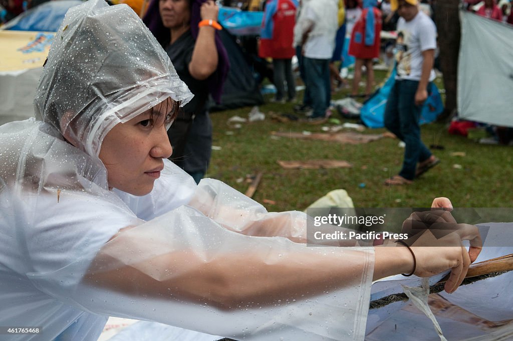 A devotee prepares her makeshift roof out of sacks  as...