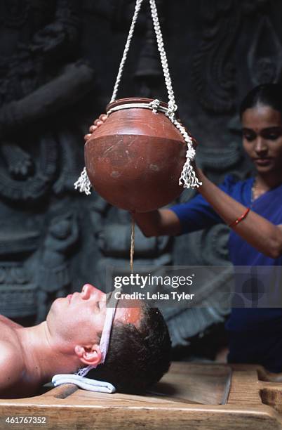 Man receiving shirodhara, a treatment from ayurveda where warm herbal oil is poured onto the head in a rhythmic fashion, curing head and brain...