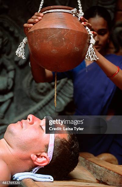 Man receiving Shirodhara - an Ayurvedic treatment where warm medicinal herbal oil is poured over the head in a rhythmic fashion.