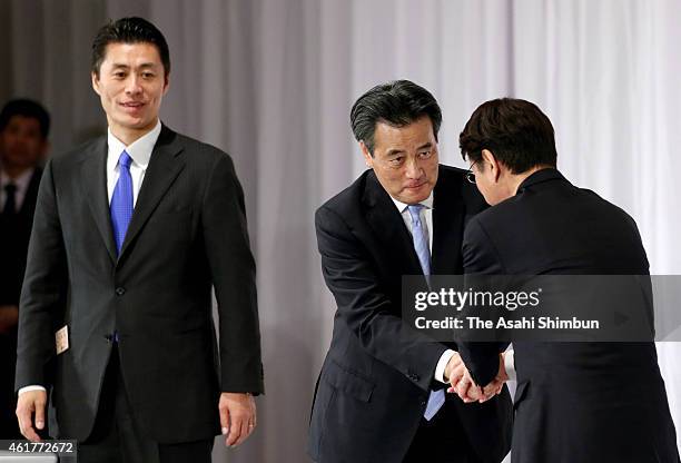 Newly elected Democratic Party President Katsuya Okada shakes hands with candidate Akira Nagatsuma while other candidate Goshi Hosono watches after...