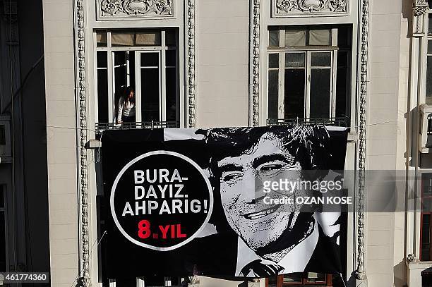 Placard bearing a picture of slain journalist Hrant Dink is hanged on the facade of Armenian newspaper "Agos" while a woman looks out the crowd...
