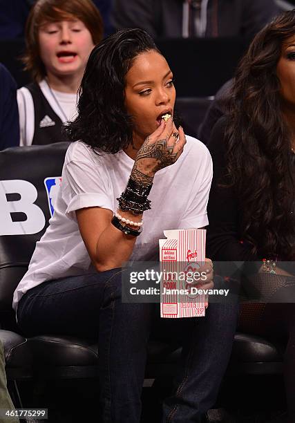 Rihanna and guest attend the Miami Heat vs Brooklyn Nets game at Barclays Center on January 10, 2014 in the Brooklyn borough of New York City.