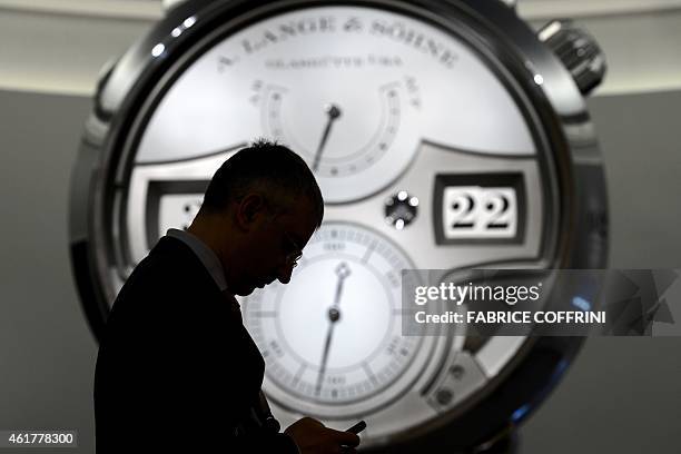 Man cheks his cellphone next to the stand of German watchmaker A. Lange & Soehne on January 19, 2015 during the opening day of the "Salon...