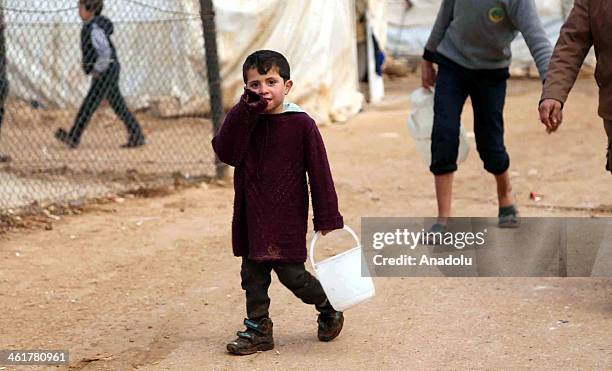 Syrian refugee kid carries an empty bucket to get food from distribution point at a refugee camp near the Es Selame border gate of Turkey on January...