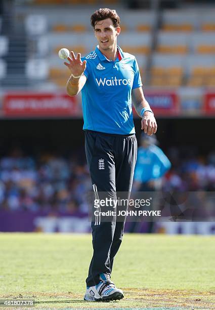 Steven Finn of England takes the ball while bowling during the tri-series one-day cricket match between England and India at the Gabba in Brisbane on...