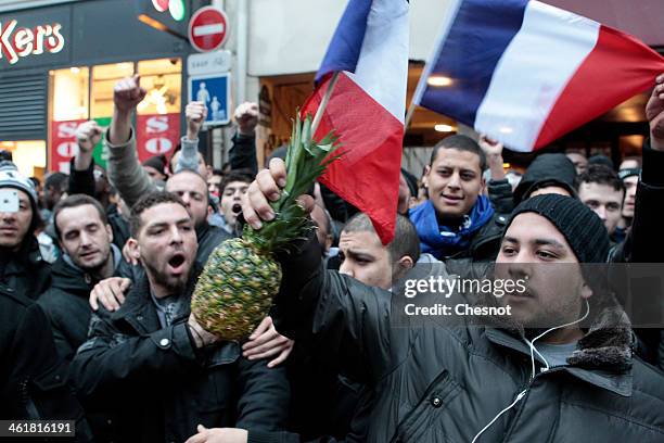 Fans of the French comic Dieudonne M'Bala M'Bala gather close to a theater in Paris, as one of them waves the French national flag and hold a...