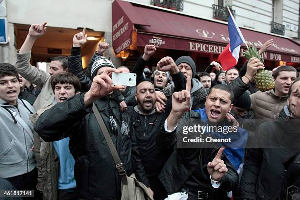 Fans of the French comic Dieudonne M'Bala M'Bala gather close to a theater in Paris, as one of them waves the French national flag and hold a...