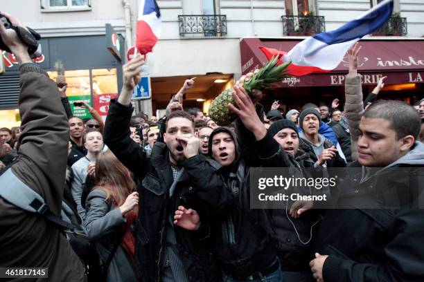 Fans of the French comic Dieudonne M'Bala M'Bala gather close to a theater in Paris, as one of them waves the French national flag and hold a...