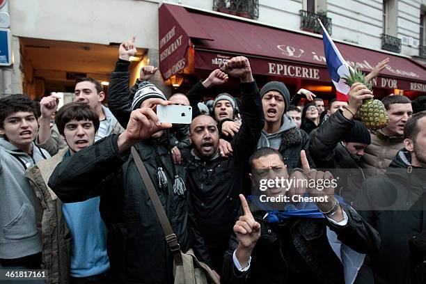 Fans of the French comic Dieudonne M'Bala M'Bala gather close to a theater in Paris, as one of them waves the French national flag and hold a...