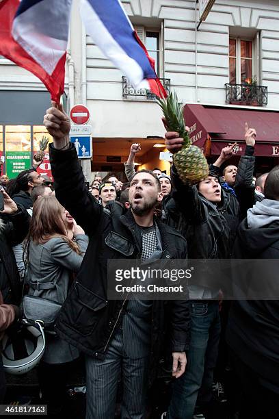 Fans of the French comic Dieudonne M'Bala M'Bala gather close to a theater in Paris, as one of them waves the French national flag and hold a...
